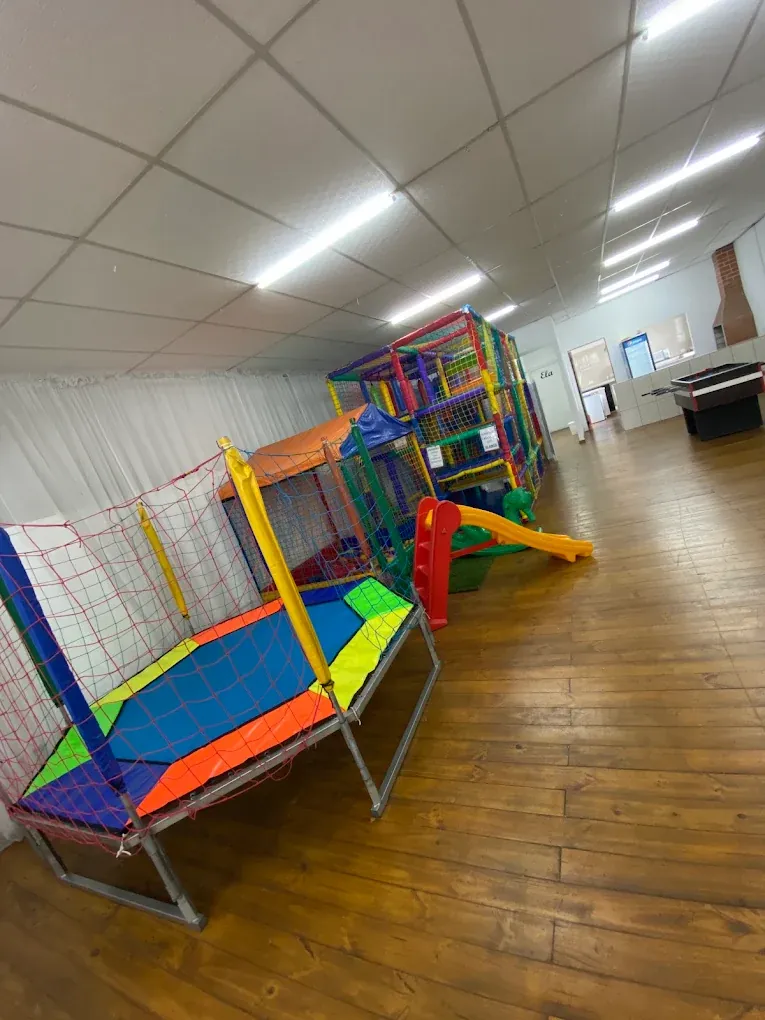 Cama elástica colorida e playground ao fundo