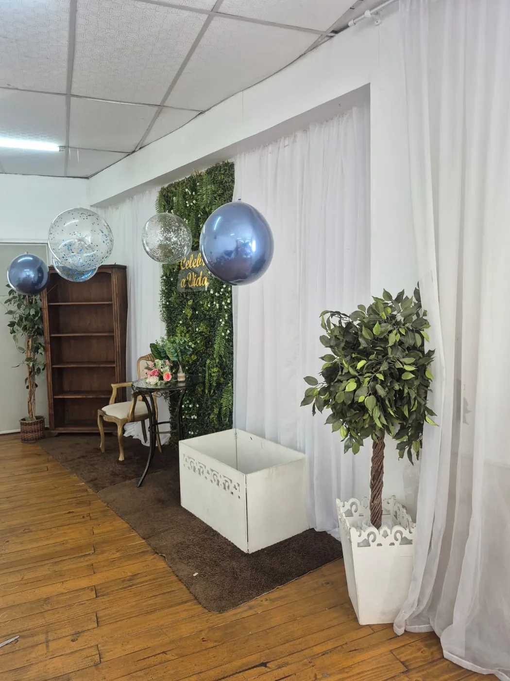 Cantinho decorado com parede verde, balões e poltrona