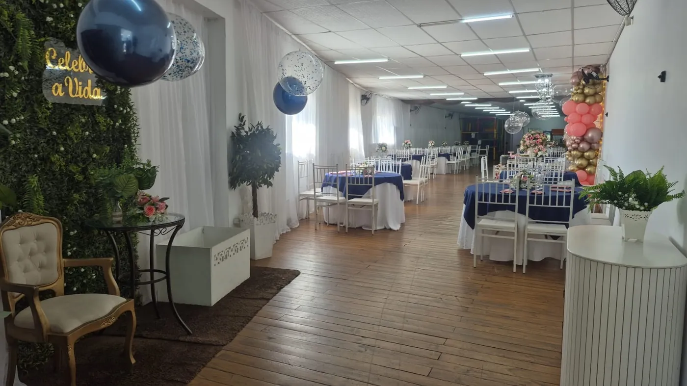 Salão com mesas azul marinho e cantinho com poltrona e plantas